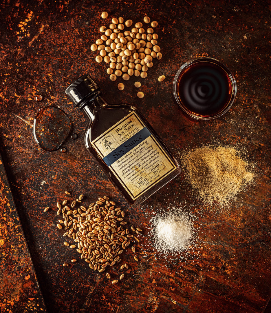 A bottle of Bluegrass Soy Sauce surrounded by small piles of raw main ingredients